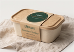 A square biodegradable container of Posture Summer Turkey fresh dog food, wrapped in a kraft paper band with a green circular label, resting on a textured beige linen cloth against a white background.